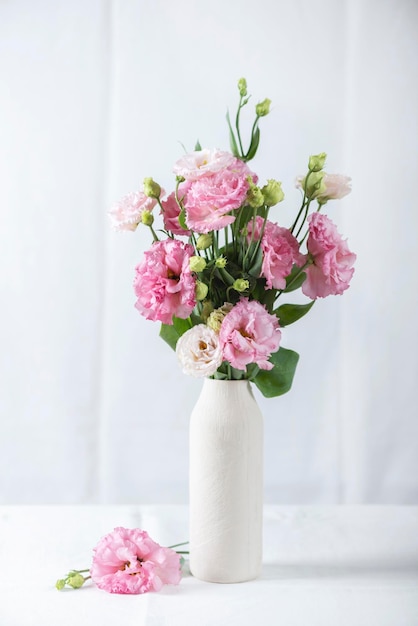 Różowe kwiaty lisianthus w białym wazonie