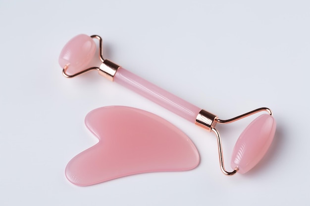 Różowe narzędzie do masażu Gua Sha na białym tle przeznaczone do walki radioelektronicznej Rose Quartz jade roller