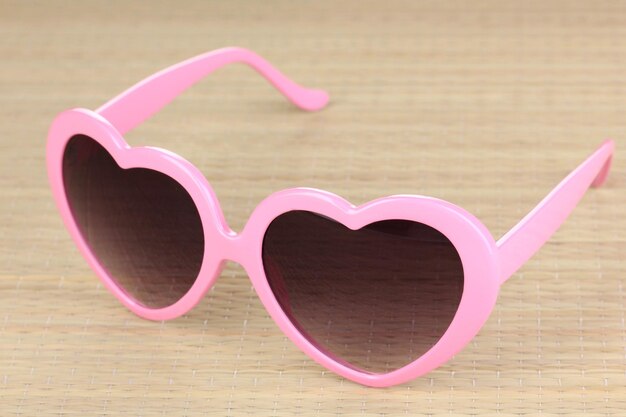 Różowe okulary przeciwsłoneczne w kształcie serca na bambusowej macie