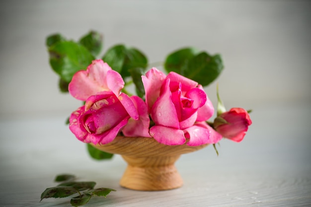 różowe piękne letnie róże na jasnym drewnianym stole