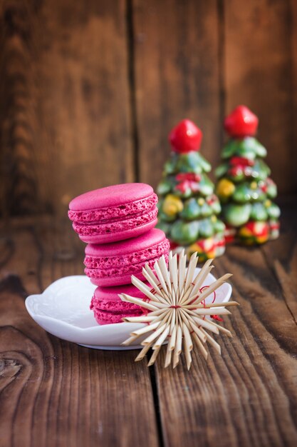 Różowi macaroons z boże narodzenie dekoracjami na woooden tle