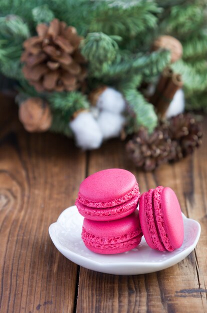 Różowi macaroons z boże narodzenie dekoracjami na woooden tle