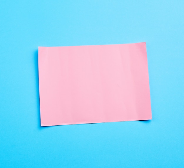 Różowy arkusz papieru na niebieskiej powierzchni