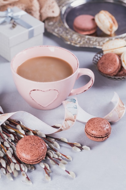 Różowy kubek kawy ze słodkimi pastelowymi francuskimi makaronikami