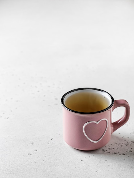 Różowy kubek z sercem herbaty stojący na białym tle z teksturą Martwa natura na walentynki
