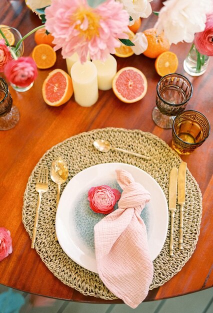Różowy kwiat leży na talerzu na wyprostowanym dywanie na świątecznym stole