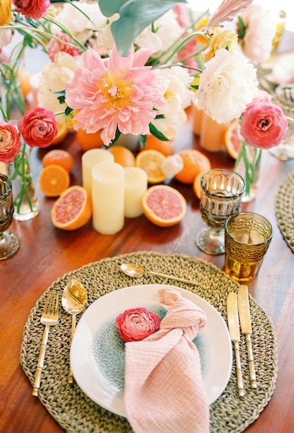 Różowy kwiat leży na talerzu obok węzłowej serwetki na wyprostowanym dywanie na stole świątecznym