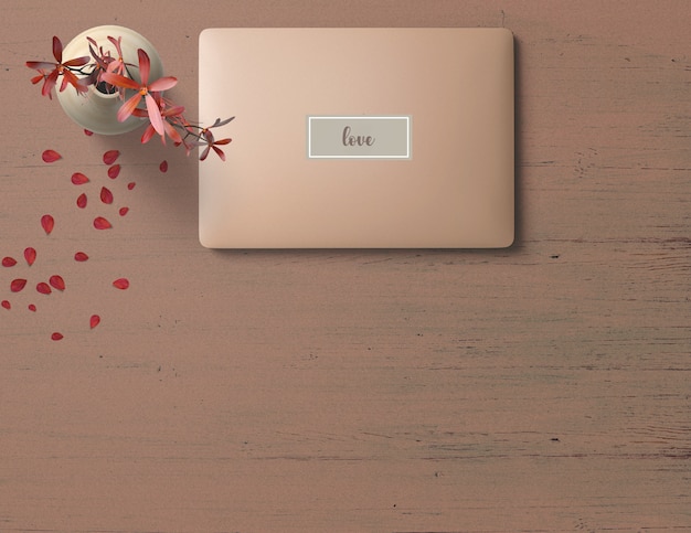 Różowy laptop na różowym drewnianym stole z czerwonym kwiatem w wazie i płatkach