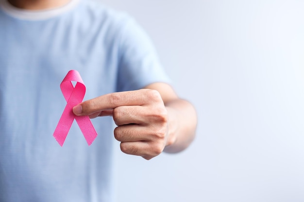 Różowy październikowy miesiąc świadomości raka piersi mężczyzna trzyma różową wstążkę dla wsparcia życia i choroby ludzi Narodowy miesiąc ocalonych z raka Koncepcja dnia matki i światowego dnia raka