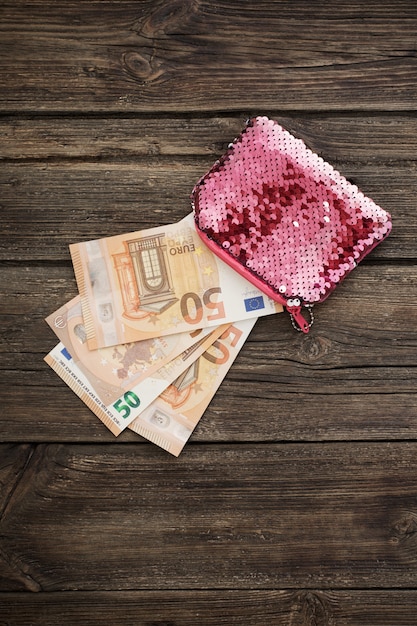 Zdjęcie różowy portfel damski z euro na starym drewnianym tle