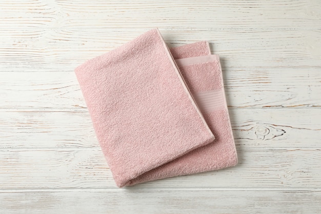 Różowy ręcznik na białym drewnianym tle, odgórny widok