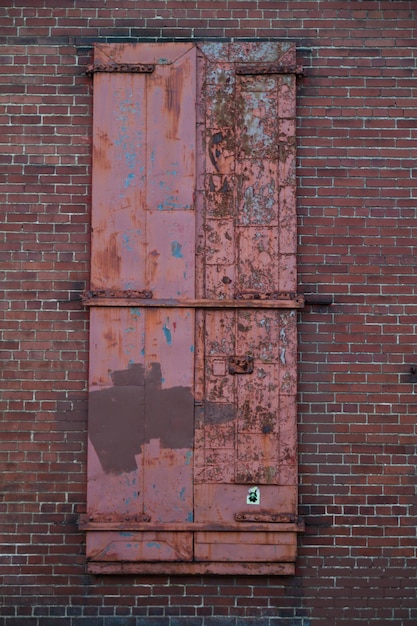 Rozpadające się czerwone drzwi w miejskiej murze z cegieł w Louisville
