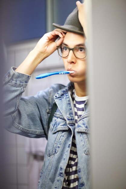 Rozpoczęcie dnia Modny młody chłopak przygotowuje się do dnia, myjąc zęby