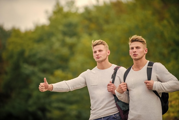 Rozpocznij wspaniałą przygodę w swoim życiu z autostopem Przyjaciele z firmy podróżujący autostopem po drodze Natura tło Podróżujący w drodze Przyjaciele autostopowicze podróżujący Autostop gest