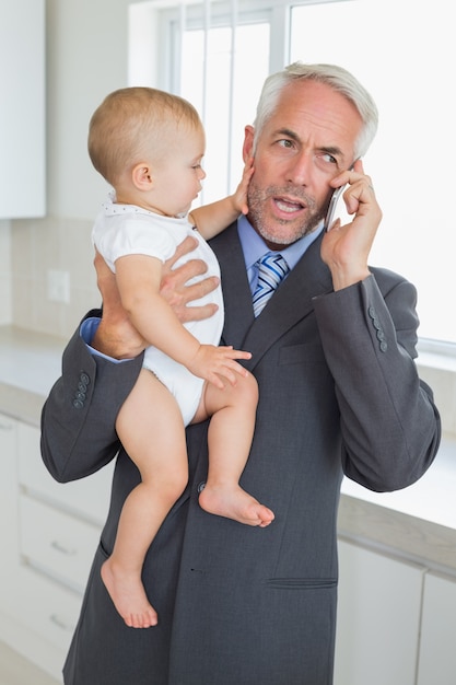 Rozpraszać uwagę biznesmen trzyma jego dziecka w ranku przed pracą