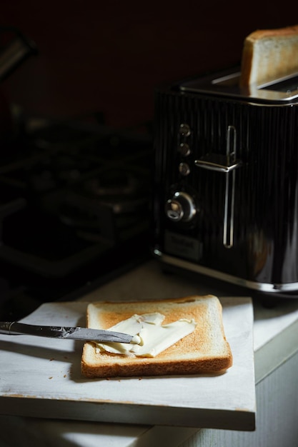 Rozprowadzanie masła na chlebie tostowym na śniadanie w retro tosterze w tle