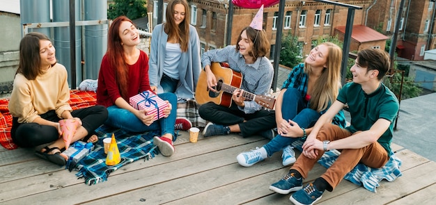 Rozrywka Młodzieży. Beztroscy młodzi ludzie śpiewają piosenki, grają na gitarze i odpoczywają. Alternatywna subkultura, nieszablonowe poglądy na życie