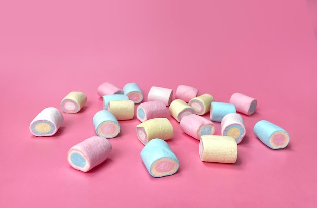 Zdjęcie rozrzucone kolorowe marshmallows na różowym tle widok boczny