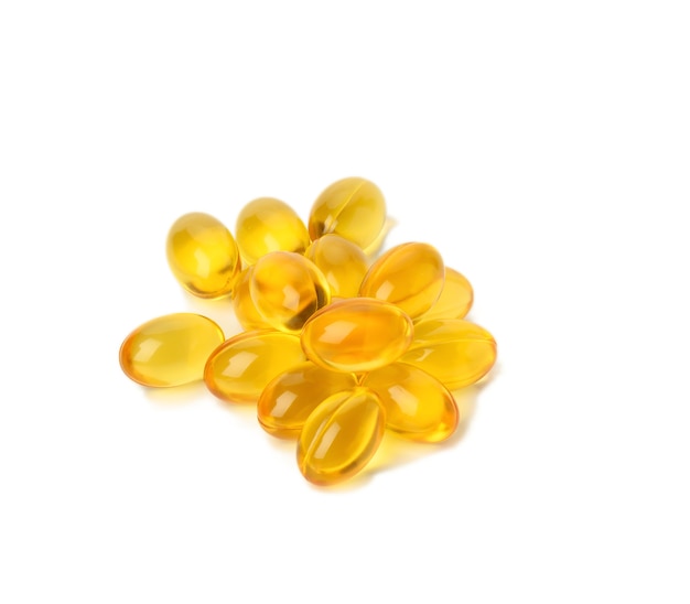 Rozsypane owalne tabletki z olejem rybim, omega 3 na białej powierzchni, z bliska