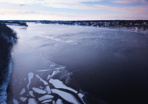 Roztopiony lód na tle zimowego krajobrazu rzeki