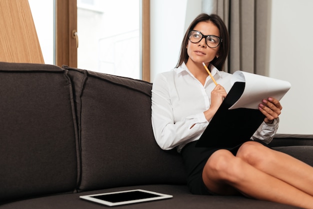 Rozważna młoda biznesowa kobieta bierze notatki podczas gdy pracujący