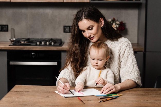 Rozwijanie lekcji rysunku dla małego dziecka w domu Urlop macierzyński Mama i mała córka rysują kredkami i wspólnie spędzają czas z mamą