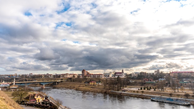 Ruch szarych chmur deszczowych nad rzeką i panorama miasta Widok na nabrzeże wzdłuż rzeki i most drogowy