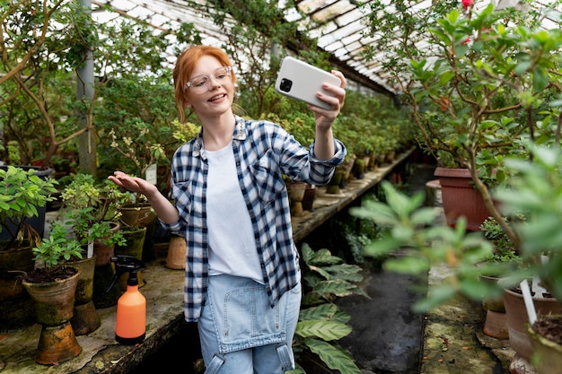 Zdjęcie ruda kobieta dbająca o swoje rośliny w szklarni
