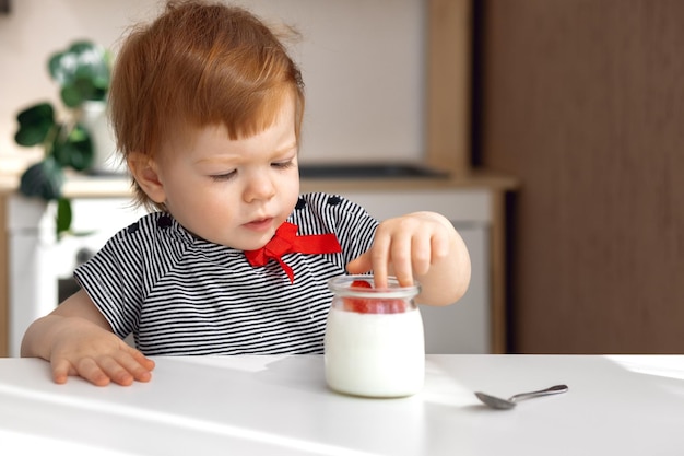 Zdjęcie ruda mała dziewczynka będzie jadła domowy jogurt z koncepcją jagód właściwe jedzenie dla dzieci