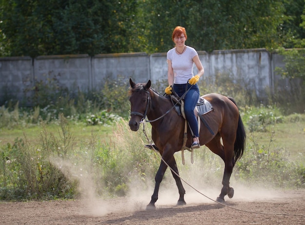 Ruda Uśmiechnięta Kobieta Jedzie Na Ciemnym Koniu Na Polu