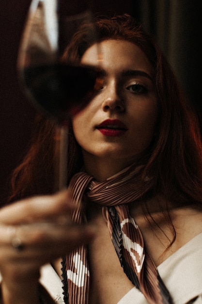 Rudowłosa kobieta wygląda wspaniale i trzyma kieliszek wina