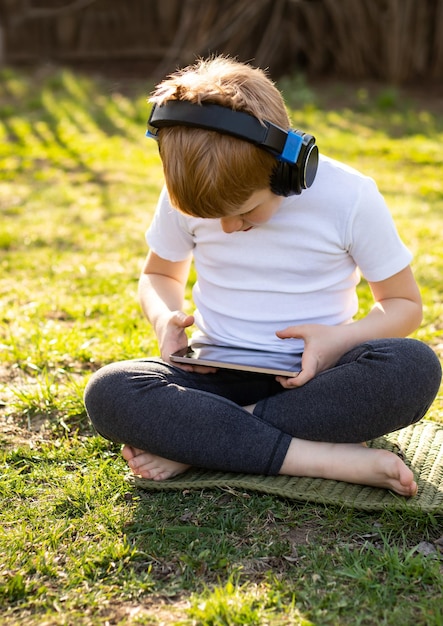 Rudowłosa nastolatka w białej koszulce z zamkniętymi oczami, słuchająca muzyki za pomocą urządzenia mobilnego