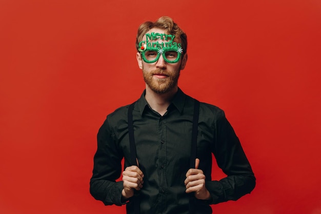 Rudowłosy przystojny mężczyzna w karnawałowych okularach na imprezie noworocznej Fotografia studyjna