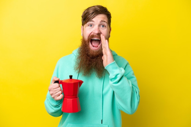 Rudy mężczyzna z brodą trzymający dzbanek do kawy na żółtym tle krzyczy z szeroko otwartymi ustami