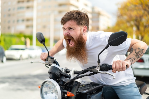Zdjęcie rudy mężczyzna z brodą z motocyklem