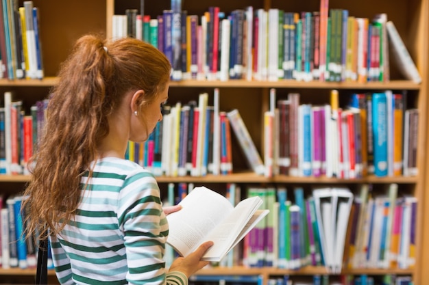 Rudy student czytanie książki z półki w bibliotece