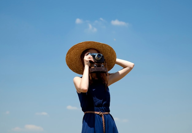 Rudzielec dziewczyna z retro kamerą przy niebieskim niebem
