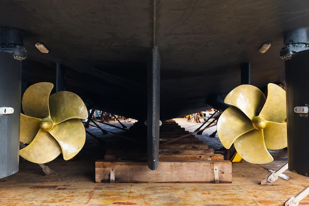 Rufa z dwoma śmigłami jachtu motorowego jest zacumowana w suchym doku na drewnianych klockach i stalowych podporach