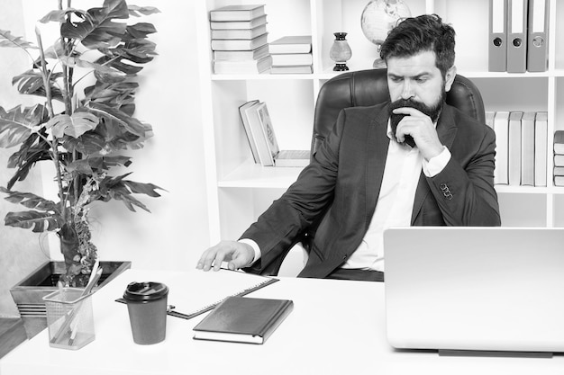 Rutyna biurowa Menedżer rozwiązujący problemy biznesowe Biznesmen odpowiedzialny za rozwiązania biznesowe Opracowywanie strategii biznesowej Ryzykowny biznes Mężczyzna brodaty szef hipster siedzi w biurze z laptopem