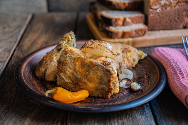 Ryba smażona na talerzu ceramicznym z przyprawami i chlebem na drewnianym stole jadalnym