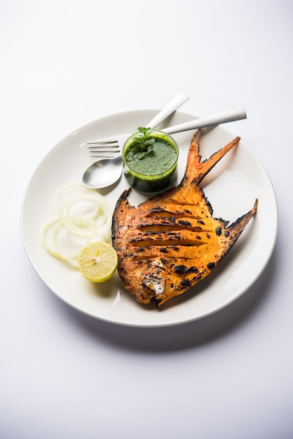 Ryba Tandoori Pomfret gotowana w glinianym piecu i przyozdobiona sałatką z cytryny, mięty, kapusty i marchewki. Selektywne skupienie