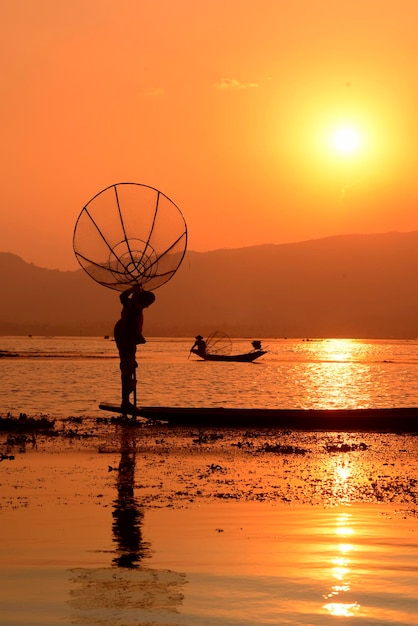 Rybacy łowiący w jeziorze na tle nieba podczas zachodu słońca