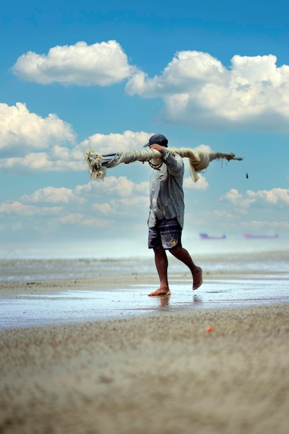 Rybak niesie sieć z plaży w hoi an.