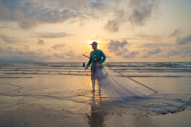 Rybak rzuca swoją sieć o wschodzie lub zachodzie słońca Tradycyjni rybacy przygotowują sieć rybacką