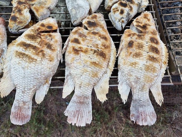 Zdjęcie ryby morskie zawinięte w sól są grillowane na węglu drzewnym na żelaznej siatce w celu sprzedaży klientom