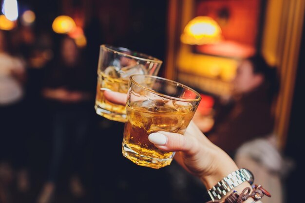 Zdjęcie rye whiskey koktajl na lodach zaraz zostanie podniesiony przez rękę kobiety