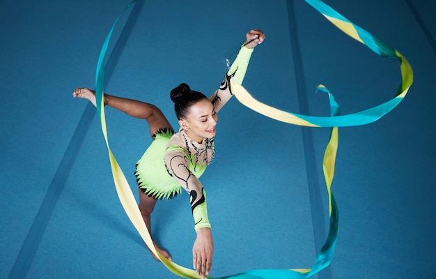Zdjęcie rytmiczna gimnastyka kobieta w siłowni i wstążce z działaniem równowagi z wydajnością i sprawnością zawodową sportowca i gimnastykka kreatywność i sztuka z rutyną tańca i energią na arenie