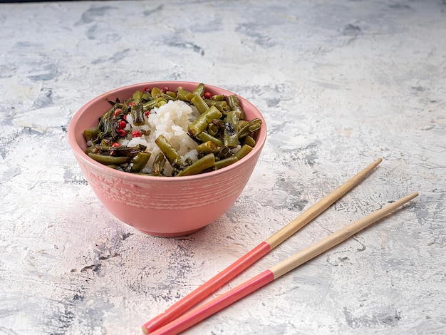 Zdjęcie ryż i zielona fasolka w ceramicznej misce z drewnianymi pałeczkami