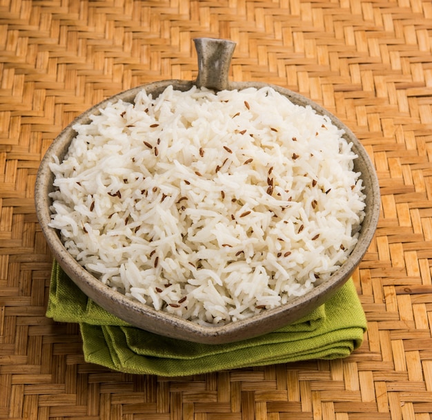 Ryż kminkowy lub indyjski ryż Jeera na kolorowym tle, selektywne skupienie