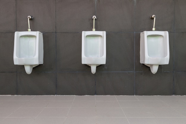 Zdjęcie rząd białego pisuaru mężczyzna jawna toaleta z popielatym ściennym tłem